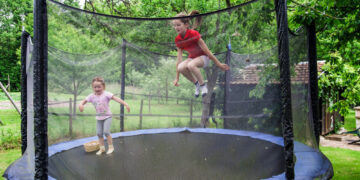 2 Kinder auf dem Trampolin im Garten